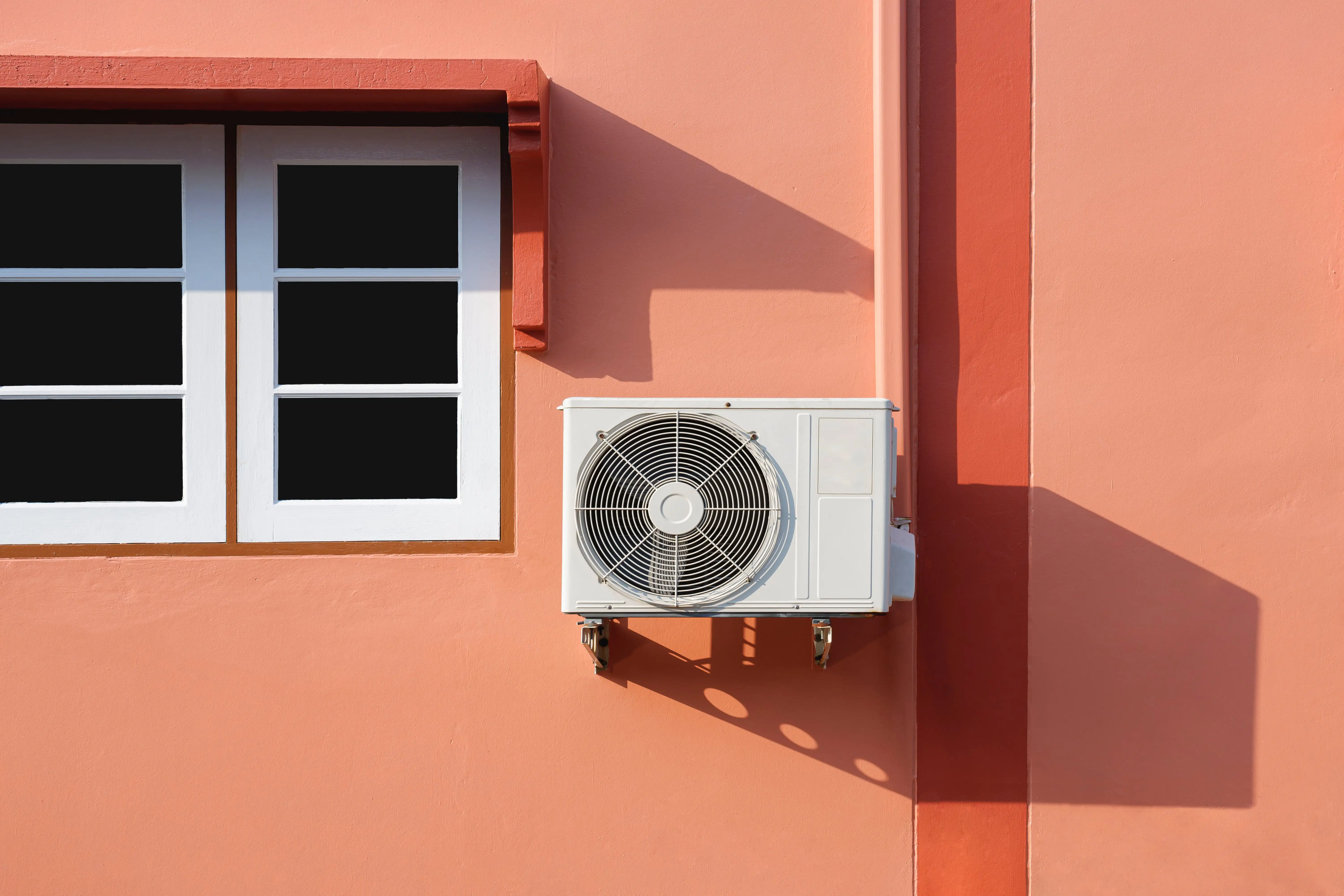Vonkajšia jednotka klimatizácie na oranžovej stene domu