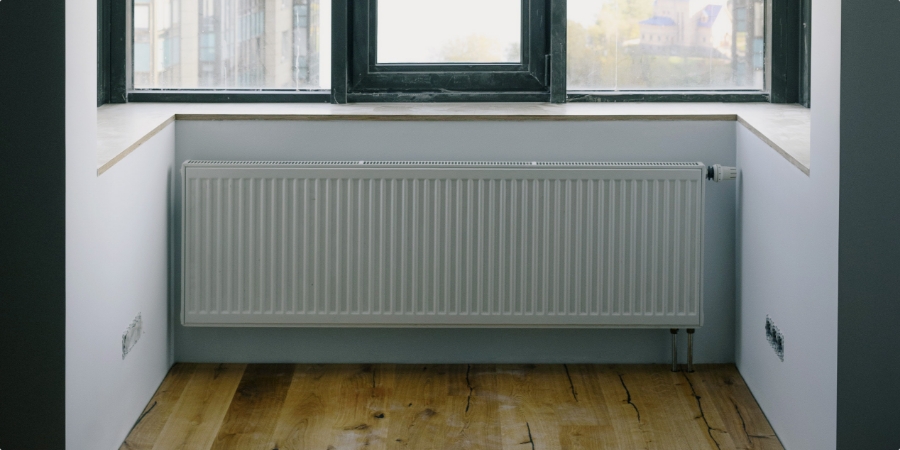 Radiátor v miestnosti s oknom, poskytujúci teplo a pohodlie.