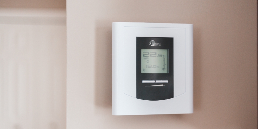 Stenový digitálny termostat regulujúci teplotu miestnosti.